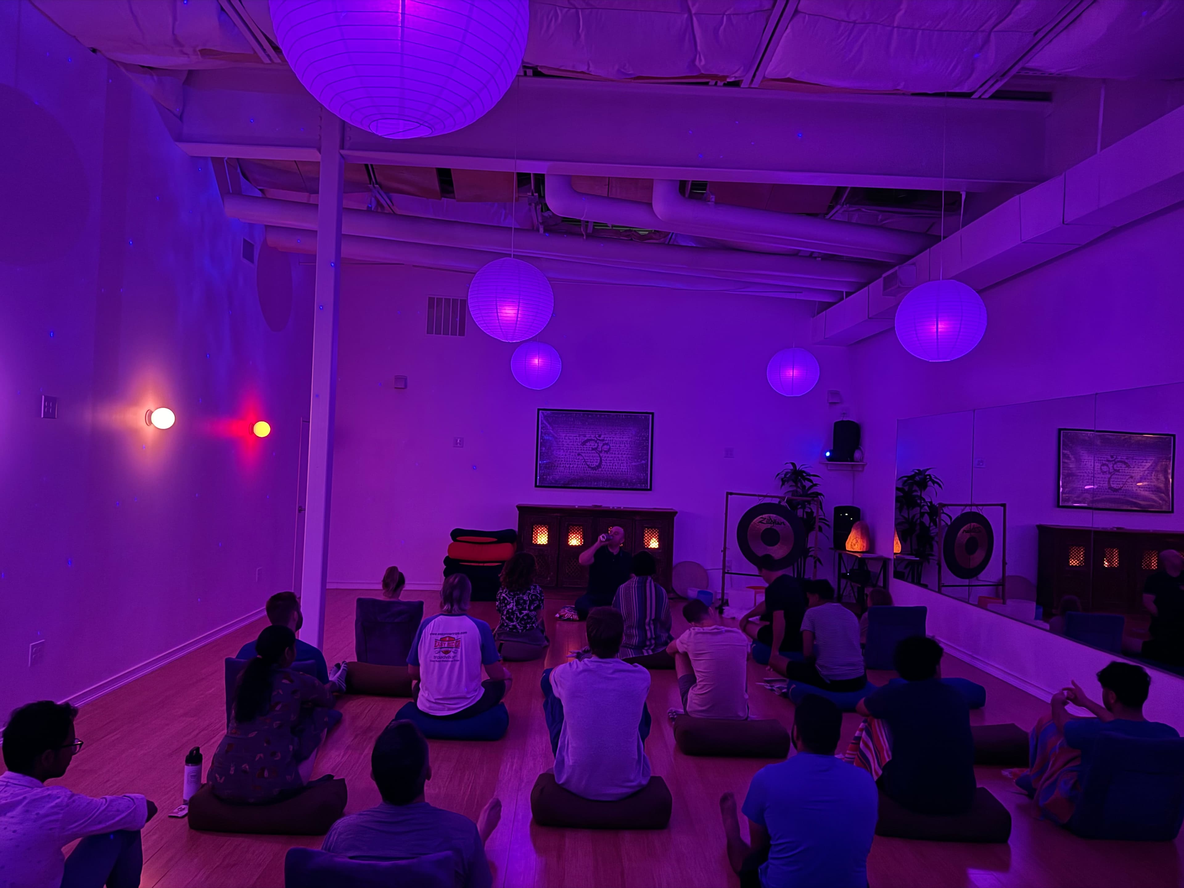 Meditation Dojo — group meditation session in purple-lit room with lanterns and gongs